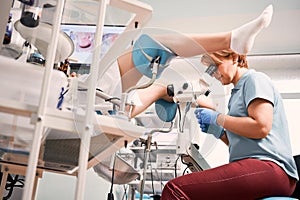 Doctor examining female patient with colposcope.