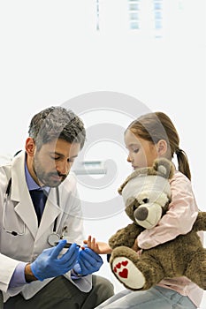 Doctor examining girl with teddybear at hospital