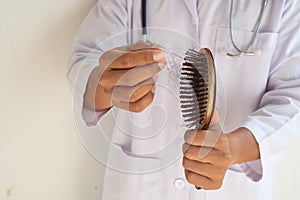 The doctor is examining the hair brush to prove hair loss.