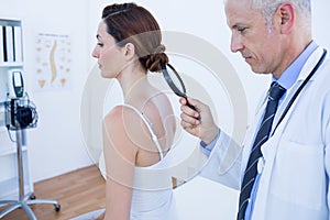 Doctor examining his patient back with magnifying glass
