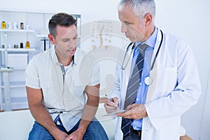 Doctor examining his patient and writing on clipboard