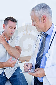 Doctor examining his patient and writing on clipboard