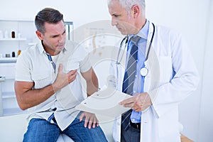 Doctor examining his patient and writing on clipboard