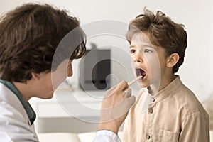 Doctor examining kid throat in medical clinic during checkup