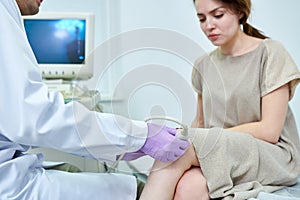 Doctor examining knee of young woman