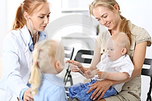 Doctor examining a little boy with stethoscope. Mother holds her son on her lap. Motherless and medicine concept