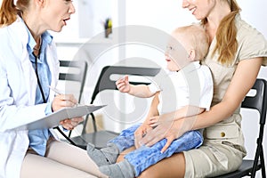 Doctor examining a little boy with stethoscope. Mother holds her son on her lap. Motherless and medicine concept