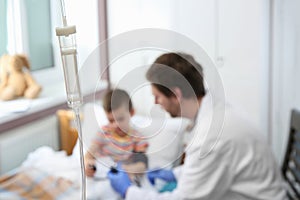 Doctor examining little child in hospital, focus chamber