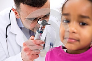 Doctor examining little girl patient's ear