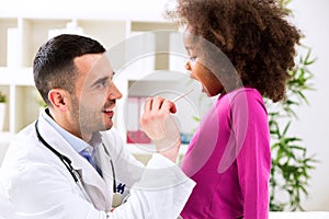 The doctor examining little girl's throat