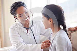 Doctor examining a little girl with stethoscope. Female paediatrician listening to childs heartbeat during home visit or