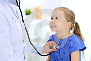 Doctor examining a little girl by stethoscope. Happy smiling child patient at usual medical inspection. Medicine and