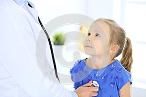 Doctor examining a little girl by stethoscope. Happy smiling child patient at usual medical inspection. Medicine and