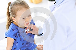 Doctor examining a little girl by stethoscope. Happy smiling child patient at usual medical inspection. Medicine and