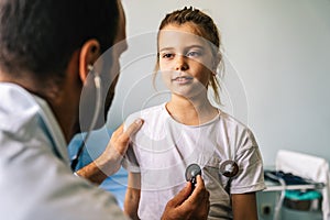 Doctor examining little girl with stethoscope in hospital. Healthcare, child, pediatrician concept.