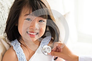Doctor examining a little girl by using stethoscope.