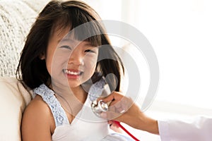 Doctor examining a little girl by using stethoscope