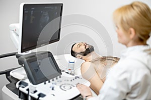 Doctor examining liver of male patient with ultrasound scan in clinic