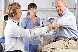 Doctor Examining Male Patient With Elbow Pain