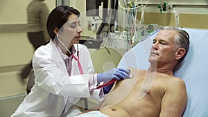 Doctor Examining Mature Male Patient In Hospital Bed