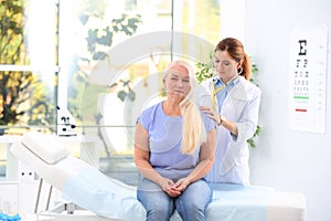 Doctor examining mature patient with stethoscope in hospital.