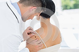 Doctor examining mole on back of woman