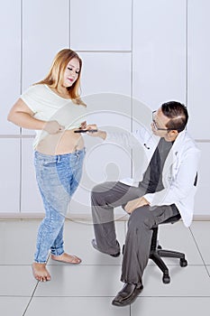 Doctor examining overweight woman stomach