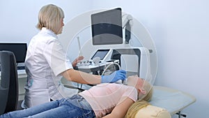 Doctor examining patient child girl thyroid gland using ultrasound scanner.