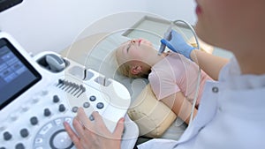 Doctor examining patient child girl thyroid gland using ultrasound scanner.