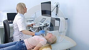 Doctor examining patient child girl thyroid gland using ultrasound scanner.