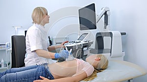 Doctor examining patient child girl thyroid gland using ultrasound scanner.