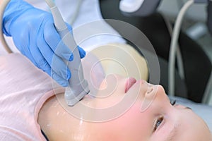 Doctor examining child girl thyroid gland using ultrasound scanner, closeup.