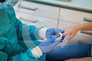 Doctor examining patient with fingertip pulse oximeter inside laboratory hospital - Focus on hand holding device