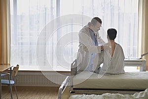 Doctor Examining Patient In Hospital Room photo