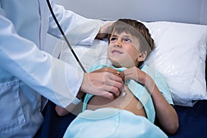 Doctor examining patient with stethoscope in ward