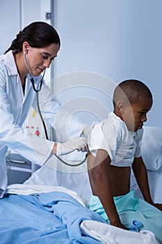 Doctor examining patient with stethoscope in ward