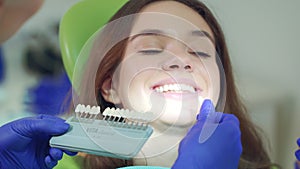 Doctor examining patient teeth whiteness. Close up dentist selecting color