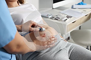 Doctor examining pregnant woman in hospital, closeup