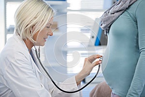 Doctor examining pregnant woman with a stethoscope