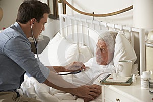 Doctor Examining Senior Male Patient In Bed At Home