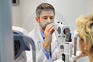 Closeup of doctor examining senior womans eye at hospital