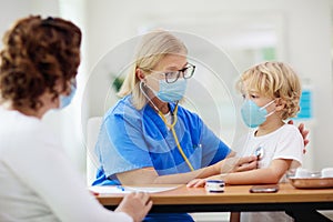 Doctor examining sick child in face mask