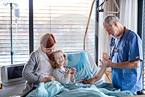 Doctor examining a small hospitalized girl with mother in hospital.