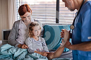 Doctor examining a small hospitalized girl with mother in hospital.