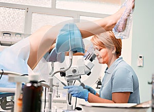 Doctor examining woman with colposcope in modern clinic.