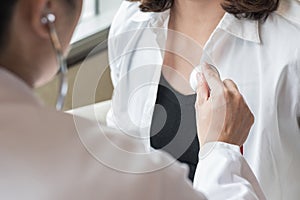 Doctor examining woman patient`s heart health checkup using stethoscope in medical clinic