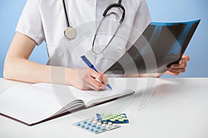 Doctor examining a X-ray photograph and making notes