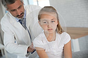 Doctor examining young girl in hospital office
