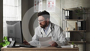 Doctor experiencing stress at work is propping head and touching his face while dealing with a challenging problem at