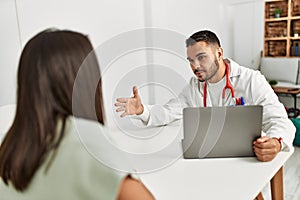 Doctor explain treatment to latin woman using laptop at clinic